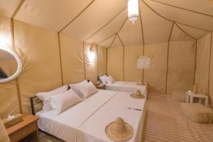 a bedroom with two beds in a tent at Sunset Camp Merzouga in Merzouga