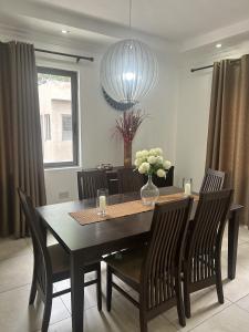 uma mesa de jantar com cadeiras e um vaso de flores em Stay Play Away Residences - Luxury 4 bed, Airport Residential, Accra em Acra