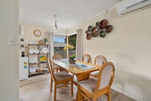 The Yellow Cottage - Turangi Holiday Home في تورانجي: مطبخ وغرفة طعام مع طاولة وكراسي خشبية