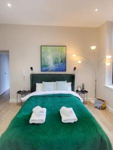 een groot groen bed met twee witte handdoeken erop bij Lovely and Modern Apartment in Leeds City Centre in Leeds