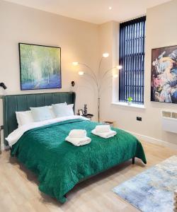 a bedroom with a large green bed with two towels on it at Stunning High Spec Apartment in Leeds City Centre in Leeds