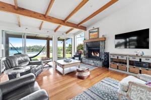 a living room with a fireplace and a tv at 923 Takatu - Tawharanui Peninsular Holiday Home in Tawharanui