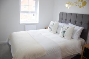 una camera da letto con un grande letto bianco con cuscini bianchi di Orient Oasis Yarm a Yarm