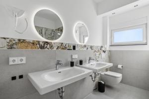 a bathroom with two sinks and a toilet and mirrors at SUITE4ME - Moderne Apartments I Küche I Balkon I Waschmaschine in Dietzenbach