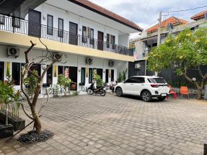 a white car parked in front of a building at MULIA INN Denpasar Imam Bonjol in Seminyak