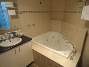 a bathroom with a bath tub and a sink at Victoria Lodge Motor Inn & Apartments in Portland +20 photos