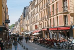 een drukke straat met mensen die lopen en tafels en stoelen bij B&B rue Royale Versailles in Versailles