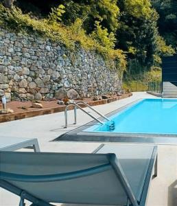 una piscina con una pared de piedra al lado en Appartamento Dany con vista lago, en Nesso