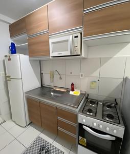 a small kitchen with a stove and a refrigerator at Viva o sonho Apt C/ar no Sim in Feira de Santana