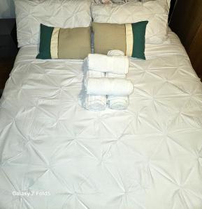 een wit bed met handdoeken en kussens erop bij LONDON FRESHAir BREATHE APARTMENT in Londen