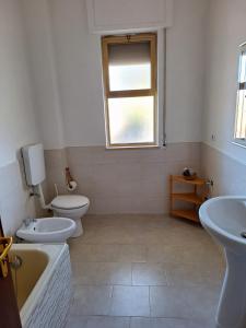 een badkamer met 2 toiletten, een bad en een wastafel bij La Casetta di Nonna Rosa in Bari