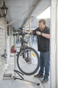 ロトルアにあるスポーツ オブ キングス モーテルの車庫の自転車の横に立つ男