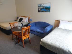 a hotel room with a bed and a table and a couch at Victoria Lodge Motor Inn & Apartments in Portland