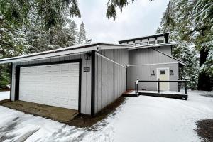 uma garagem com duas portas e neve no chão em Whispering Trees em Fish Camp