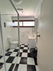 a bathroom with a toilet and a black and white checkered floor at Camelot in Yamba