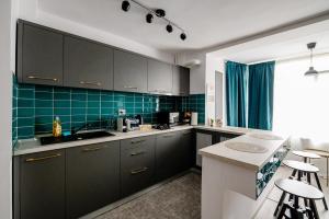 una cocina con armarios negros y azulejos verdes en Happy Heart Hideaway, en Bucarest