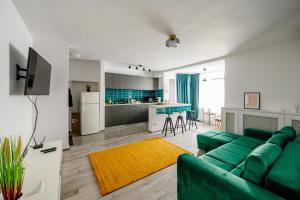 Una sala de estar con un sofá verde y una cocina. en Happy Heart Hideaway, en Bucarest