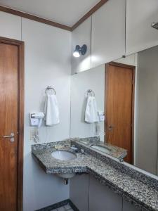 a bathroom with a sink and a mirror at Apart hotel Champagnat in Belo Horizonte