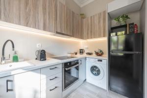 eine Küche mit einem schwarzen Kühlschrank und einem Geschirrspüler in der Unterkunft Iris Peacock's The Garden in Piräus