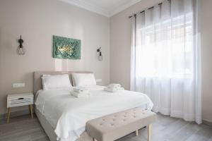 a white bedroom with a large bed and a window at Iris Peacock's The Garden in Piraeus