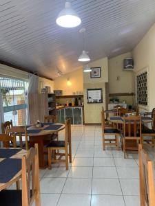 a restaurant with tables and chairs and a kitchen at Pousada Vila Regina in Penha