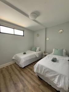 two beds in a room with white walls and wood floors at Emy's City Center Flat at 77 on Independence in Windhoek