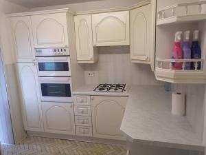 a kitchen with white cabinets and a stove top oven at MossBank House Luton Airport in Luton