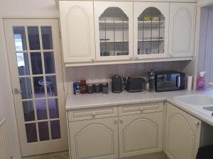 a kitchen with white cabinets and a sink at MossBank House Luton Airport in Luton