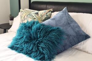 een kussen met blauwe veren op een bed met kussens bij Convenient & cosy 3 bed house in Newport