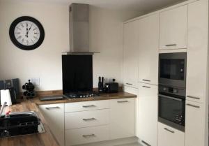 uma cozinha com armários brancos e um relógio na parede em Convenient & cosy 3 bed house em Newport