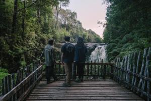 un grupo de tres personas caminando sobre un puente sobre una cascada en Lodge Parque Tepuhueico en Castro