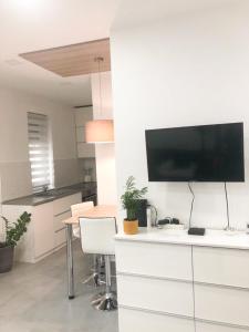 eine weiße Küche mit einem Schreibtisch und einem TV an der Wand in der Unterkunft London Apartman Szeged in Szeged