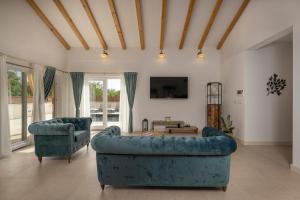 ein Wohnzimmer mit 2 blauen Sofas und einem TV in der Unterkunft Villa Jakov in Murvica