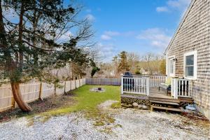 Un patio trasero con una cerca y un porche de madera. en Sand Dollar Dreams, en Harwich
