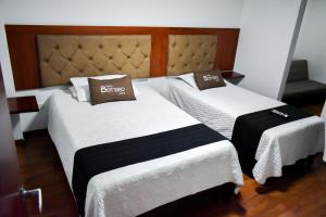 duas camas num quarto de hotel com branco e preto em Hotel Casa Botero 205 em Bogotá