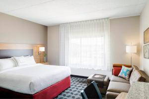 um quarto de hotel com uma cama e um sofá em TownePlace Suites by Marriott Detroit Taylor em Taylor