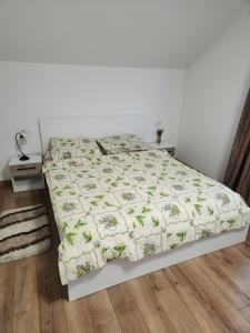Una cama blanca con edredón en un dormitorio en Casa CLO, en Sighetu Marmaţiei