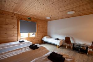 two beds in a room with wooden walls at Gladheimar Guesthouse in Blönduós