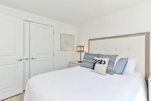 a white bedroom with a white bed with blue pillows at Harbourtown Suites, Unit 216 in Plymouth