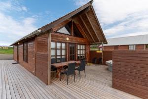 a building with a wooden deck with a table and chairs at Gladheimar Cottages in Blönduós