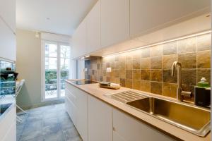 eine Küche mit weißen Schränken und einer Spüle in der Unterkunft La Serrisienne 8 - Val d'Europe - Disneyland Paris - 8 à 10 Personnes in Serris