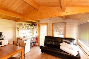 a living room with a leather couch and a kitchen at Gladheimar Cottages in Blönduós