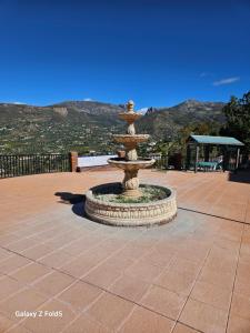 una fontana nel mezzo di un patio con montagne sullo sfondo di Piso acogedor en Alcaucin ad Alcaucín
