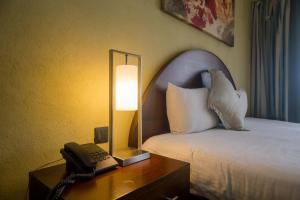 um quarto de hotel com uma cama e um telefone numa mesa em Taarifa Suites by Dunhill Serviced Apartments em Nairobi