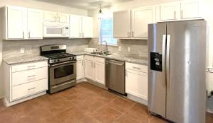 uma cozinha com armários brancos e um frigorífico de aço inoxidável em Private room pleasant grove em Dallas