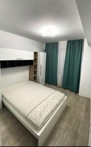 a bedroom with a white bed and green curtains at Bucharest luxury apartments Bragadiru in Bragadiru
