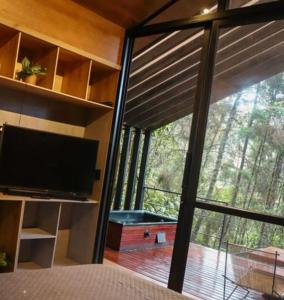 a bedroom with a large window with a television at Oculto refugio de bosque in Envigado