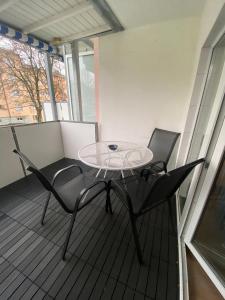 un tavolo in vetro e 2 sedie sul balcone di Zentrale 4-Zimmer-Wohnung in Sirnach a Sirnach