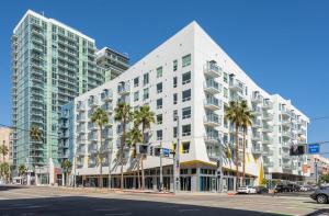 a large white building on a city street with palm trees at Level Long Beach - East Village in Long Beach