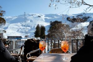 two glasses on a table with a view of a mountain at Falls Creek Hotel in Falls Creek